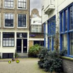 Amsterdamse binnenplaats met gesloten voordeuren en een kinderfiets op de stoep