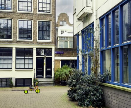 Amsterdamse binnenplaats met gesloten voordeuren en een kinderfiets op de stoep