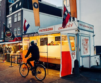 Friteskraam en fietsers op de Albert Cuypmarkt in Amsterdam tijdens de avondspits