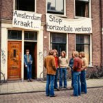 Jonge activisten staan voor een Amsterdams woonhuis met spandoeken “Amsterdam kraakt” en “Stop horizontale verkoop”, symbool van de kraakbeweging en de strijd om betaalbare huisvesting.