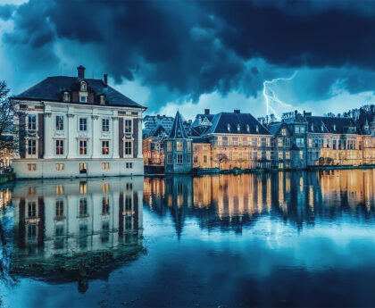 Het Binnenhof in Den Haag bij schemering met verlichte ramen en reflectie in het water
