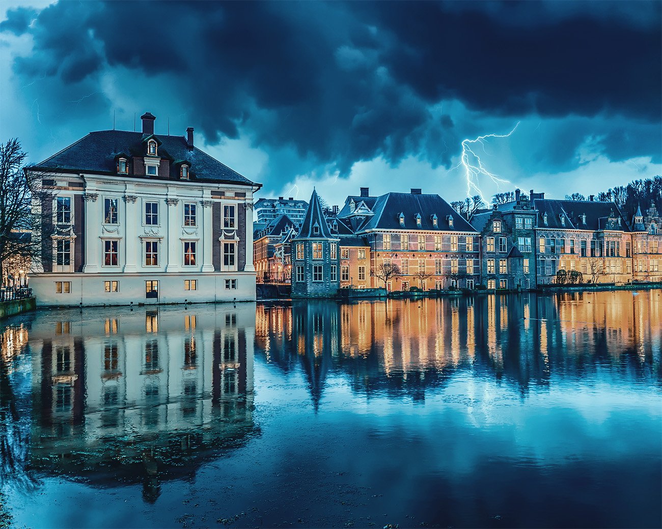 Het Binnenhof in Den Haag bij schemering met verlichte ramen en reflectie in het water