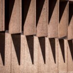 Geometrische betonnen gevel met herhalende uitstekende elementen die diepe schaduwen werpen
