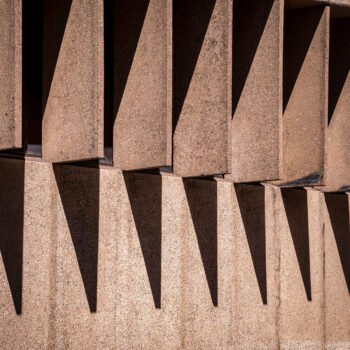 Geometrische betonnen gevel met herhalende uitstekende elementen die diepe schaduwen werpen