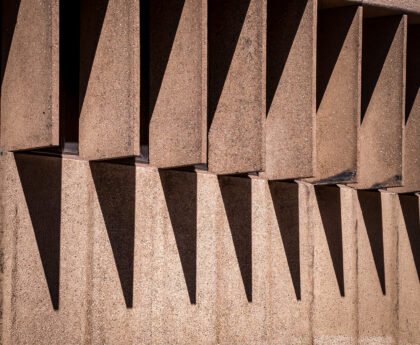 Geometrische betonnen gevel met herhalende uitstekende elementen die diepe schaduwen werpen