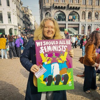 Demonstrant op de Dam in Amsterdam met een bord “We should all be feminists” tijdens een feministische bijeenkomst.