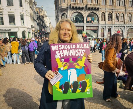 Demonstrant op de Dam in Amsterdam met een bord “We should all be feminists” tijdens een feministische bijeenkomst.