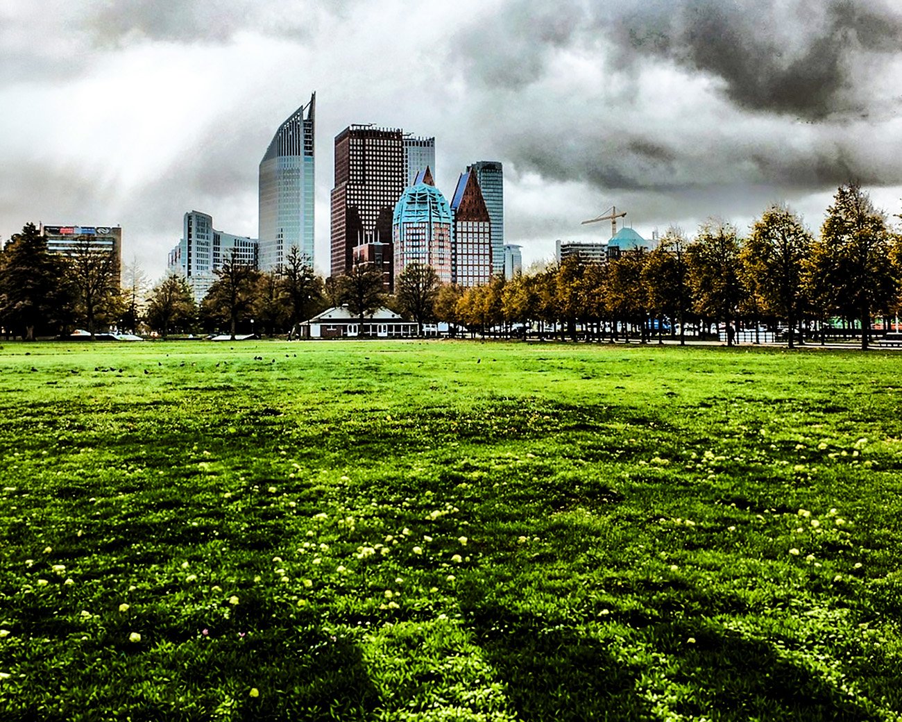 Het Malieveld in Den Haag met de skyline van ministeries en kantoren onder een dreigende lucht
