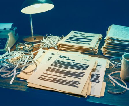 Dossiers met zwart gelakte namen en passages op een bureau onder een bureaulamp