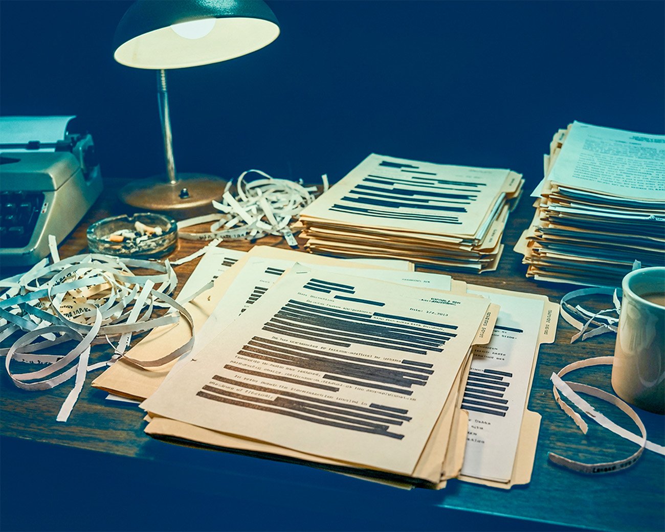 Dossiers met zwart gelakte namen en passages op een bureau onder een bureaulamp
