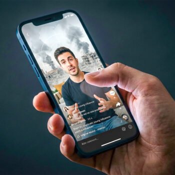 Hand met smartphone waarop een influencer-video te zien is voor beelden van verwoesting en rook, als verbeelding van digitale propaganda rond Israël en Gaza