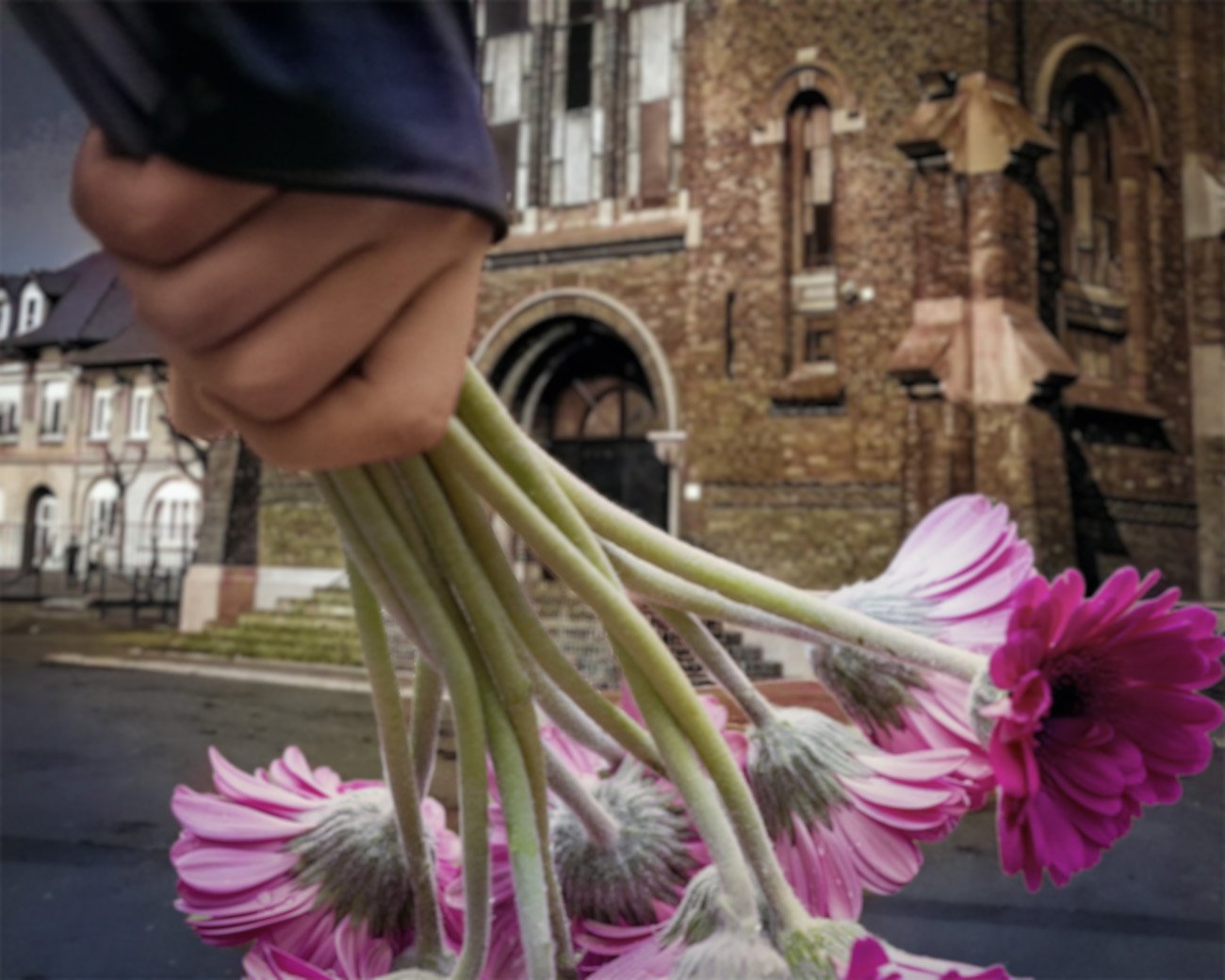 Hand met roze bloemen voor de Saint-Amé-kerk in Liévin, waar de mijnwerkersramp van 1974 wordt herdacht.