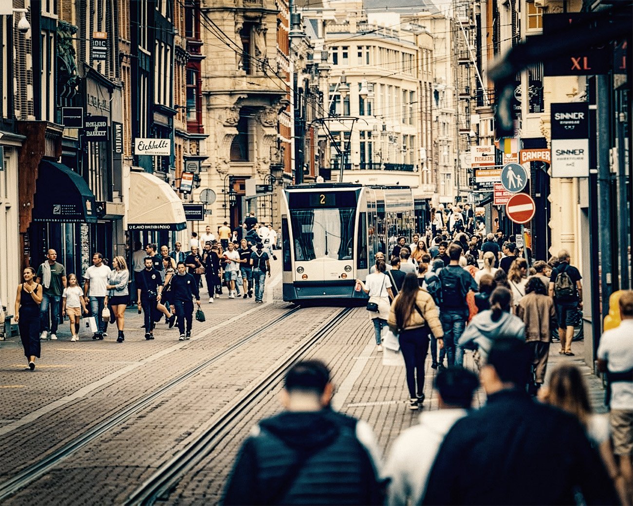 Drukke Leidsestraat in Amsterdam met voetgangers en een tram, als beeld van dagelijkse haast en stedelijke druk.