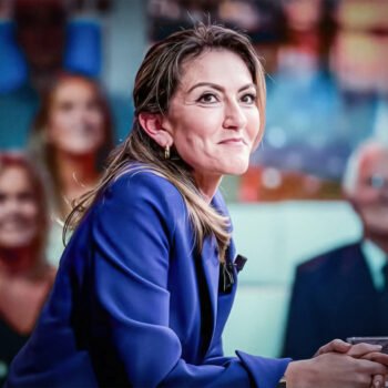 Politicus aan een talkshowtafel met publiek op de achtergrond, tijdens een gesprek over persoonlijke verhalen en politieke macht.