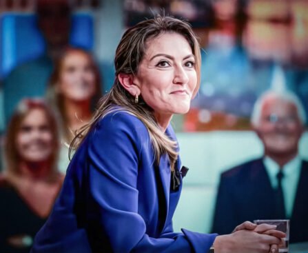 Politicus aan een talkshowtafel met publiek op de achtergrond, tijdens een gesprek over persoonlijke verhalen en politieke macht.