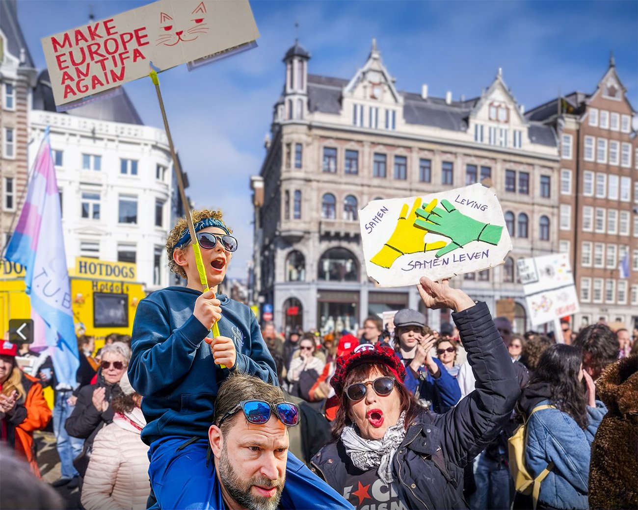 Demonstranten in Amsterdam houden borden omhoog tegen fascisme en voor samenleven, met een kind op iemands schouders op de voorgrond.