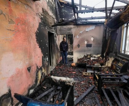 Palestijnse man staat tussen verbrande muren, verkoolde balken en puin in een huis na een aanval door Israëlische kolonisten in Fundokumiyya.