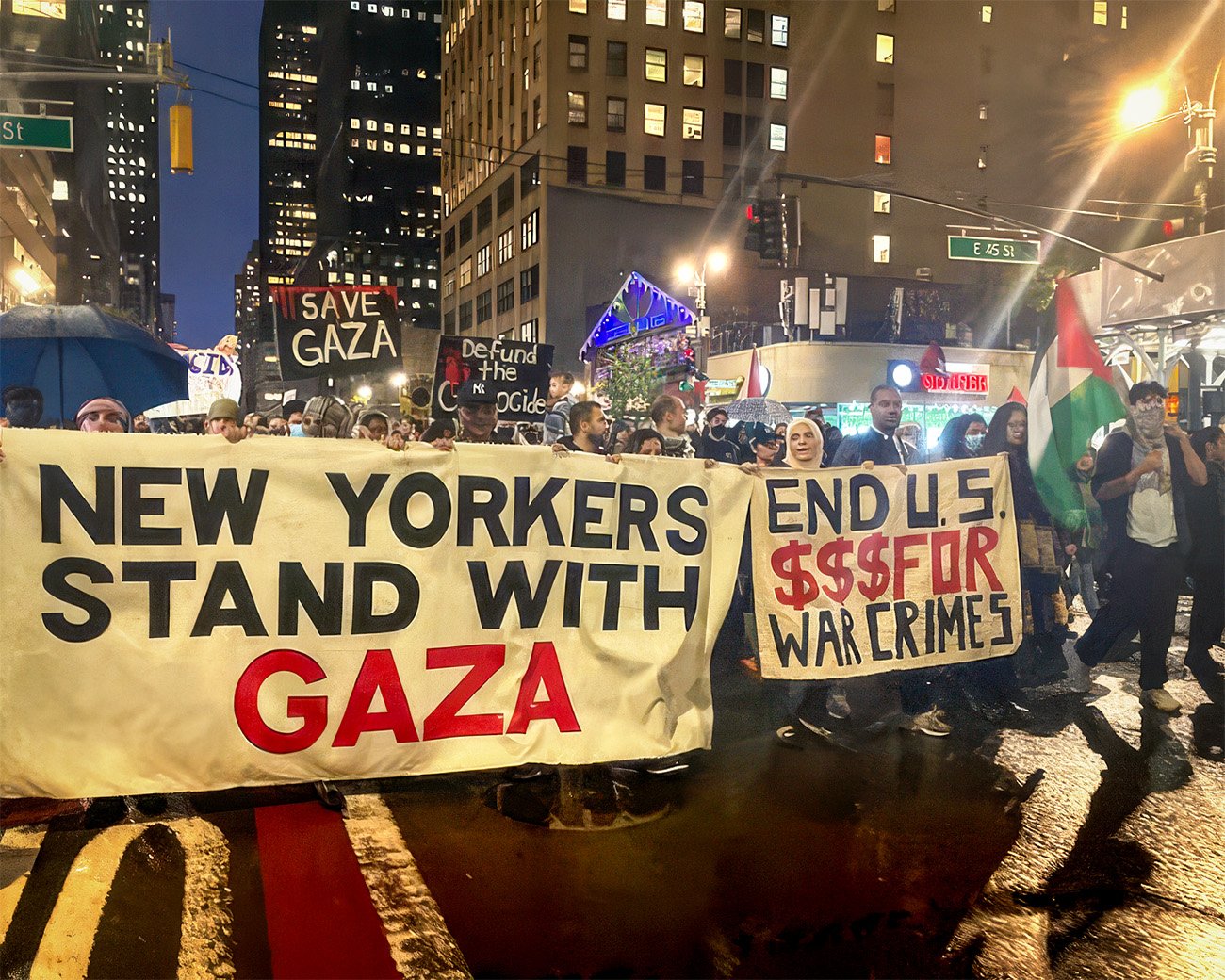 Demonstranten in New York lopen met een groot spandoek met de tekst “New Yorkers stand with Gaza” en borden tegen oorlogsmisdaden.