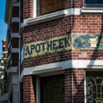 Gevel van een Amsterdams gebouw met het woord apotheek op tegels boven de ingang.
