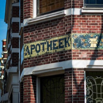 Gevel van een Amsterdams gebouw met het woord apotheek op tegels boven de ingang.