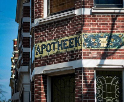 Gevel van een Amsterdams gebouw met het woord apotheek op tegels boven de ingang.