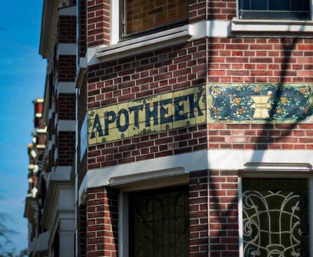 Gevel van een Amsterdams gebouw met het woord apotheek op tegels boven de ingang.