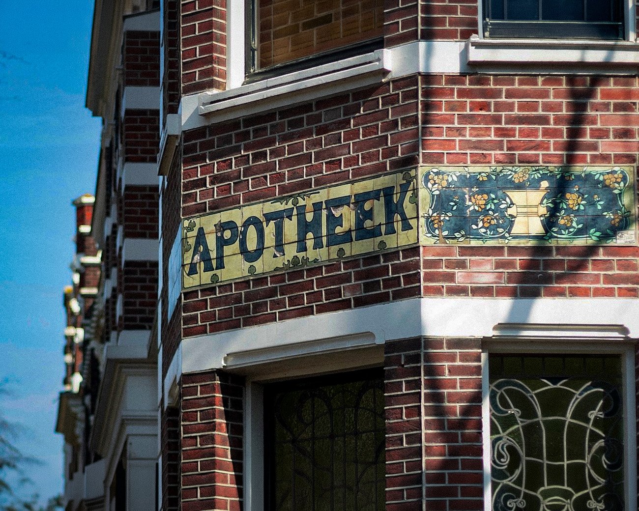 Gevel van een Amsterdams gebouw met het woord apotheek op tegels boven de ingang.