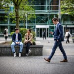 Werkende mensen voor kantoorgebouwen op de Amsterdamse Zuidas, waar de financiële wereld en het dagelijks leven samenkomen.