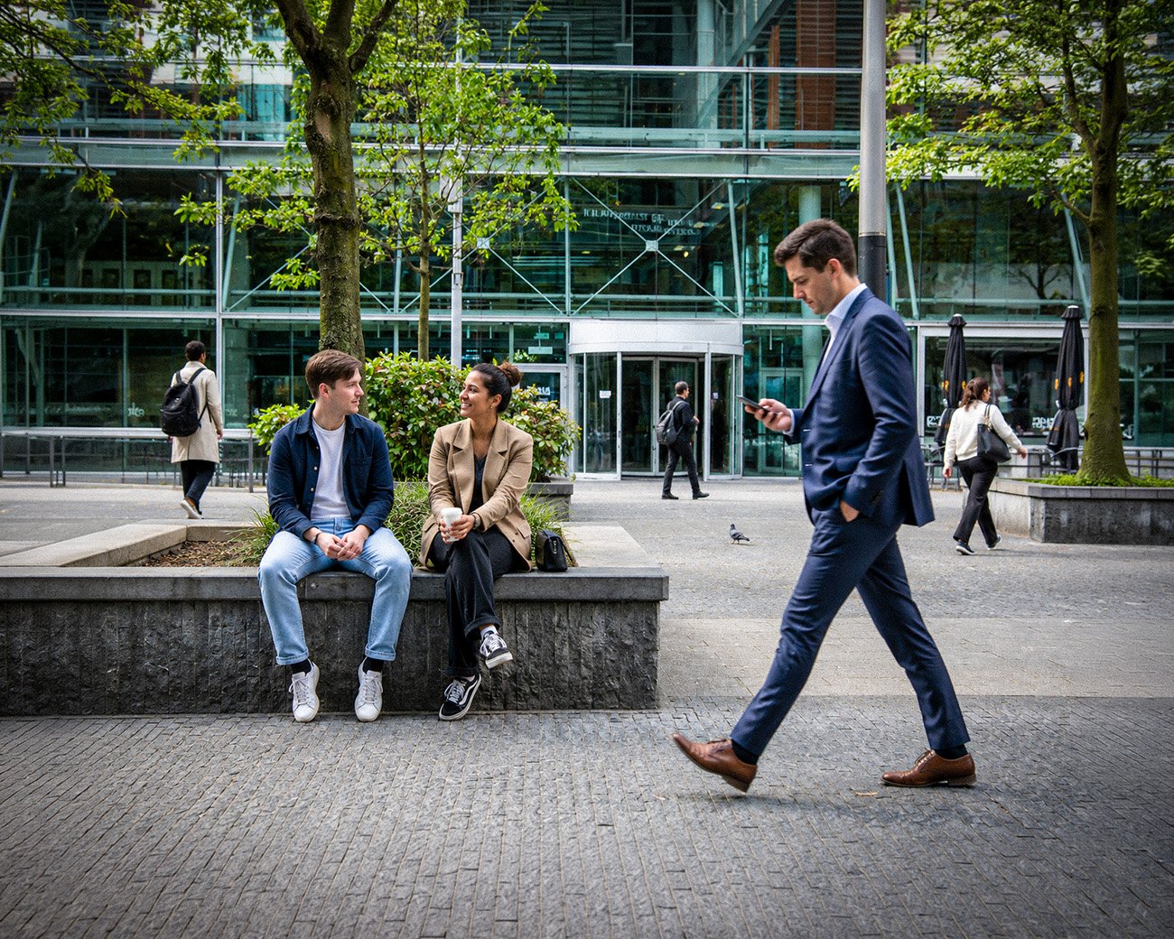 Werkende mensen voor kantoorgebouwen op de Amsterdamse Zuidas, waar de financiële wereld en het dagelijks leven samenkomen.