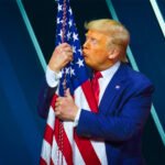 Donald Trump kust een Amerikaanse vlag tijdens een politieke bijeenkomst.