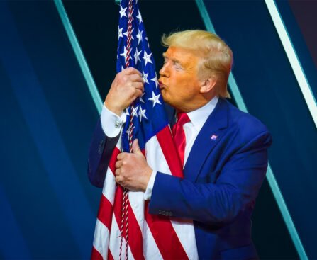 Donald Trump kust een Amerikaanse vlag tijdens een politieke bijeenkomst.